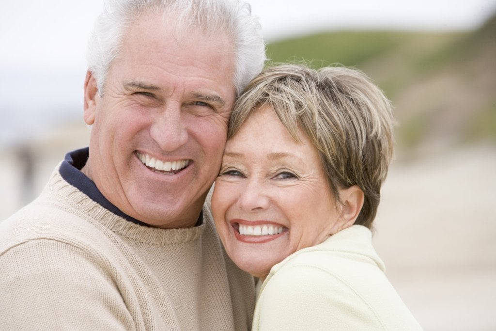 A happy couple smiles after successful oral surgery.